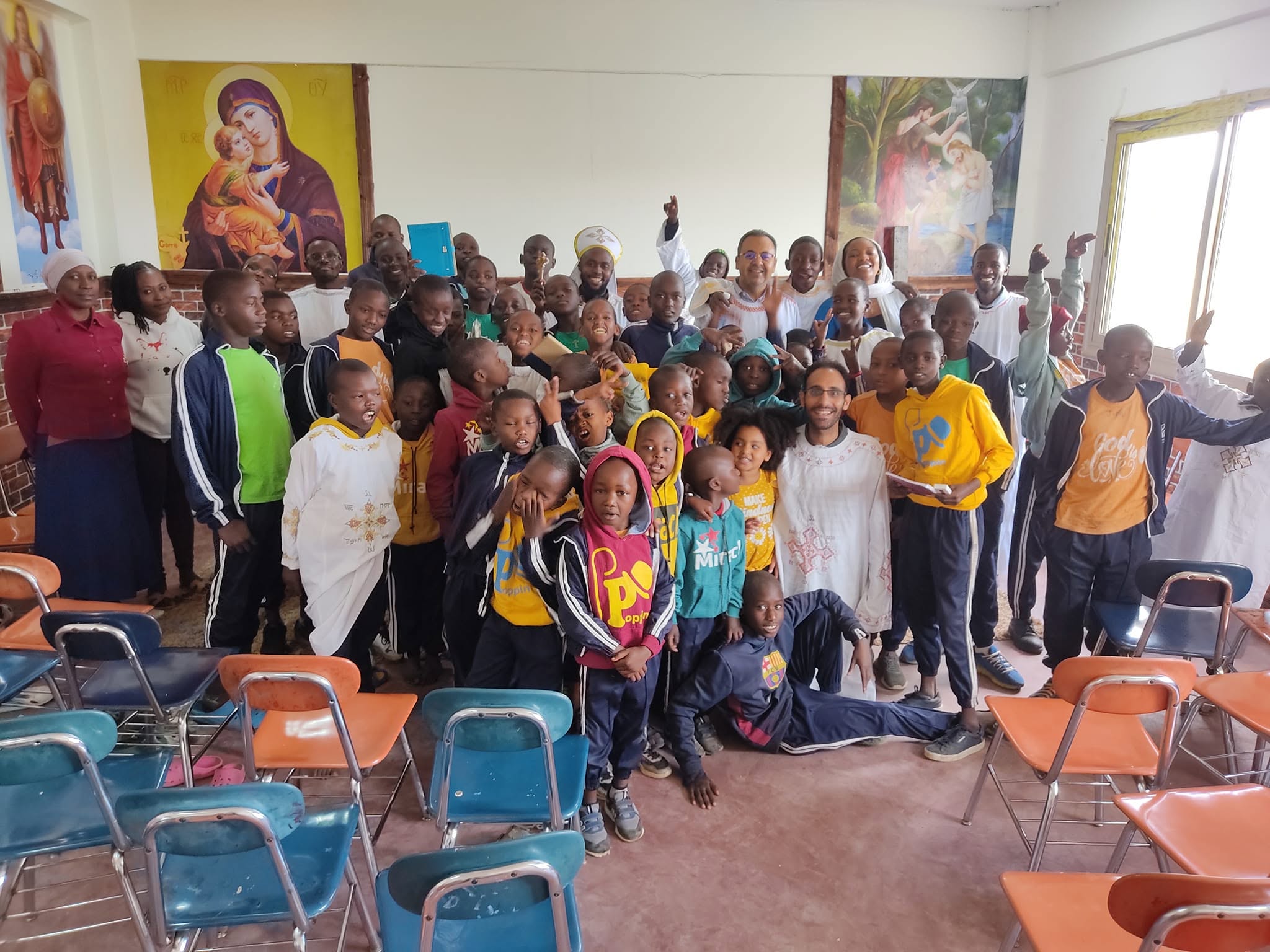 The whole Raha Kids family — boys, caregivers and clergy — celebrating together in a classroom decorated with painted icons